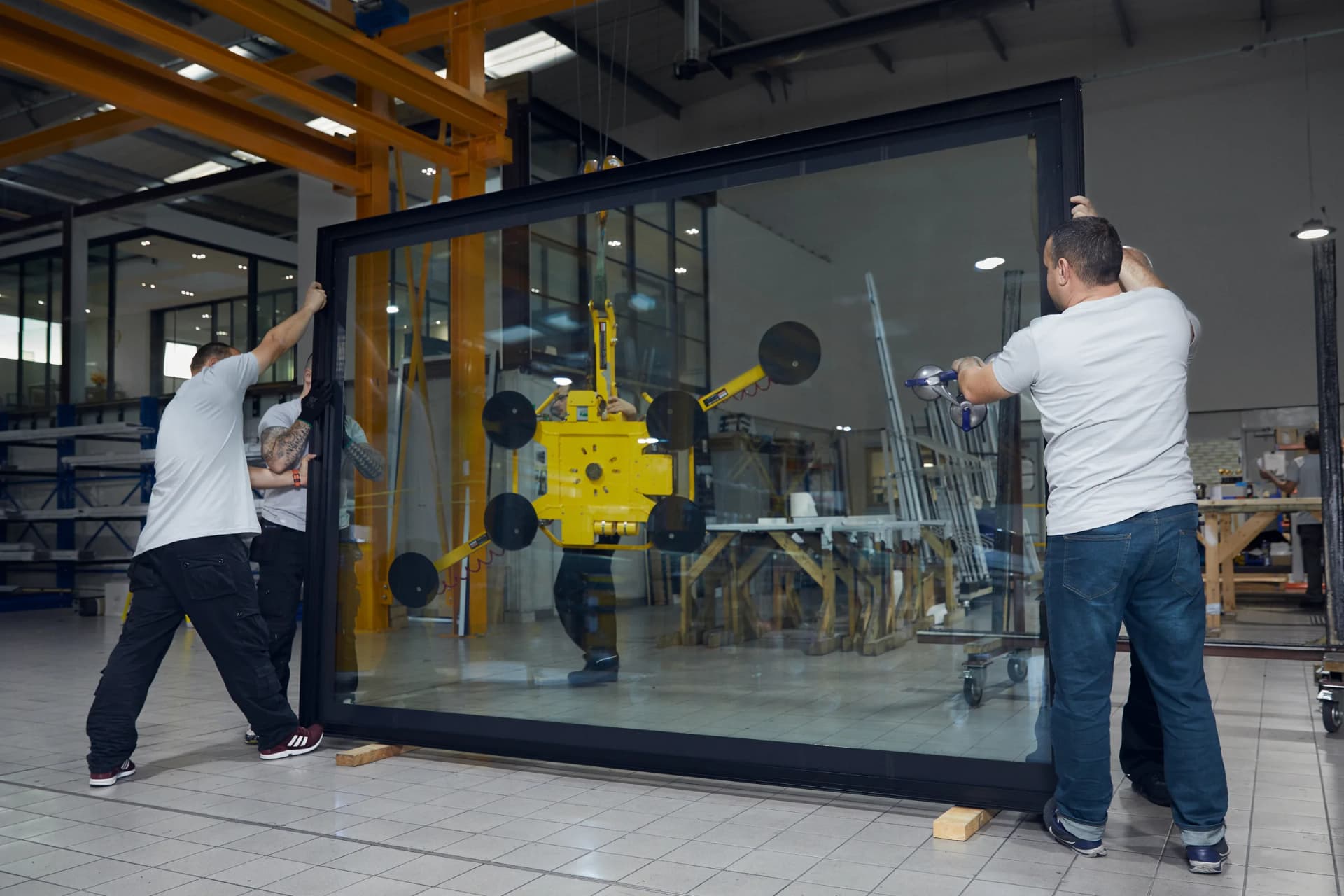 Maxlight fitting team handling a large architectural glazing unit inside the Acton factory