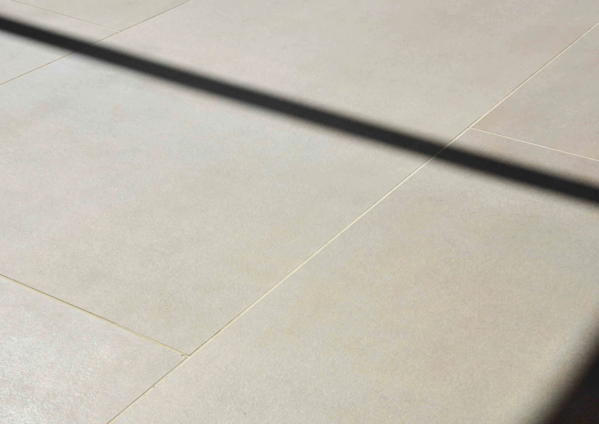 Diagonal shadows from the glazing cross pale floor tiles.