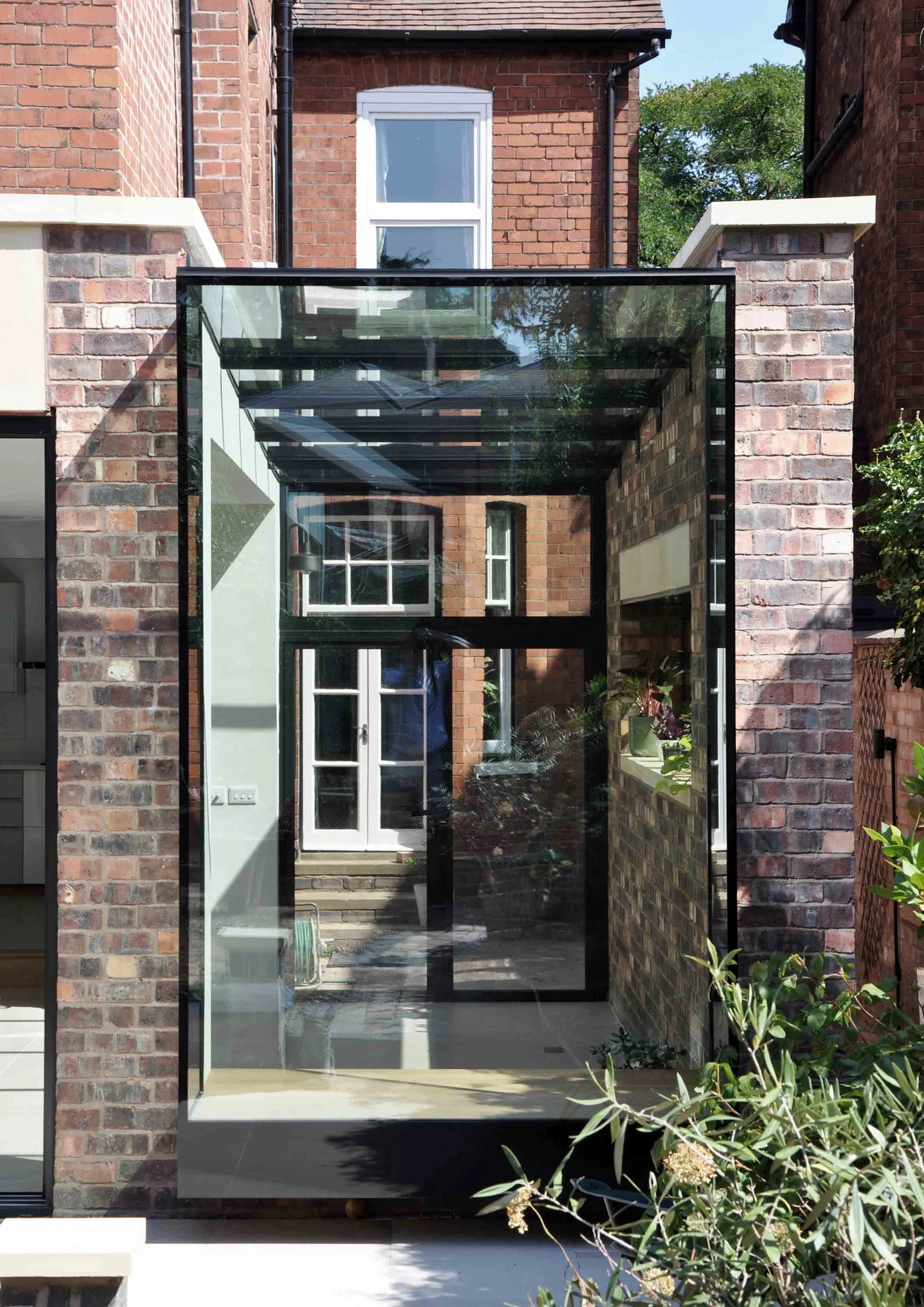 Front view of the projecting glass bay between brick piers, with its glazed roof and raised base visible.
