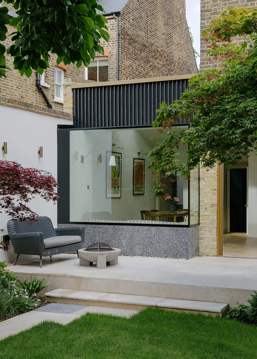 Projecting glazed Oriel Bay window beside a brick wall and garden terrace