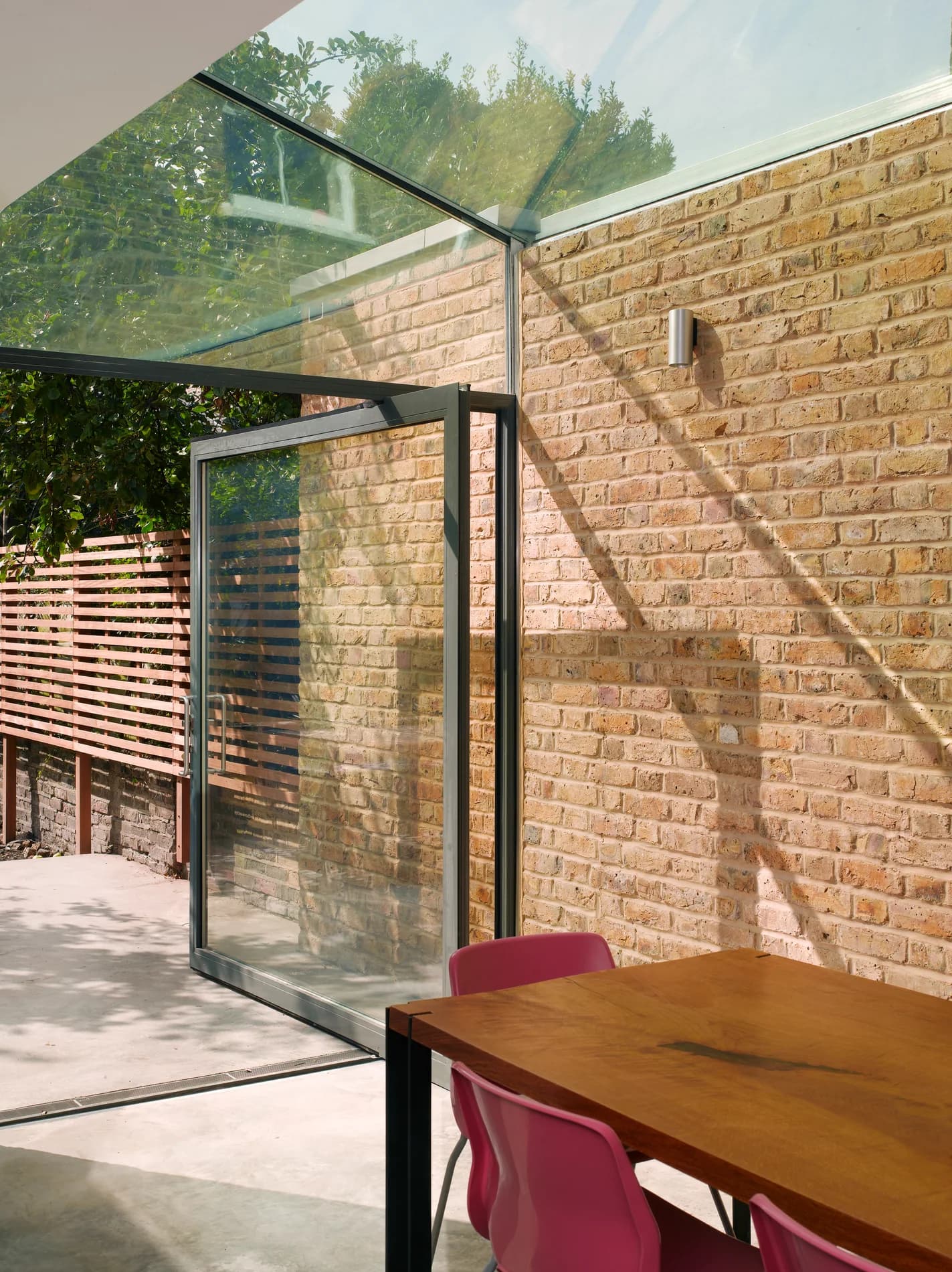 X-Max steel-inspired pivot door beside brickwork and structural glass
