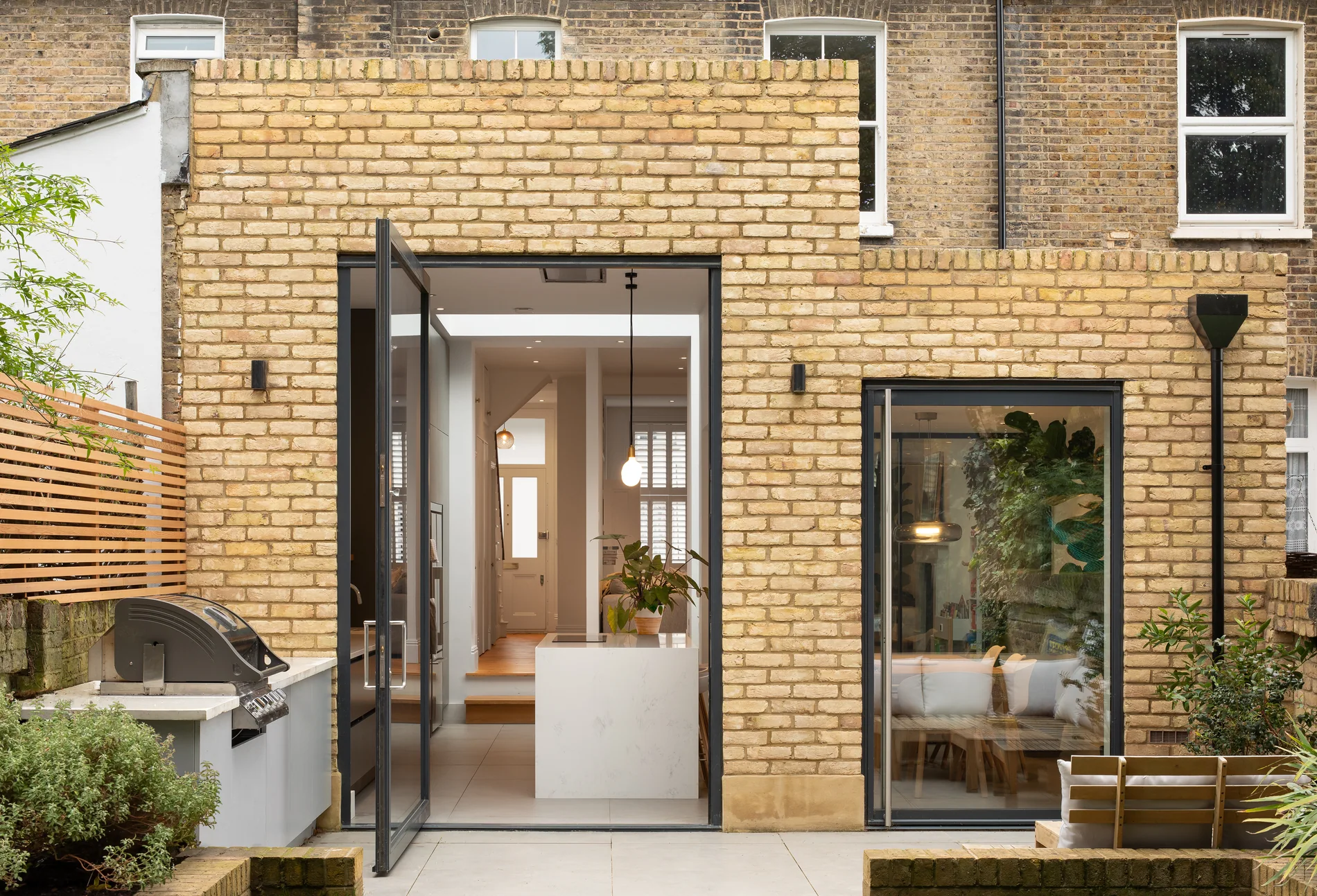 Small S-Max pivot door in a brick rear elevation beside garden seating
