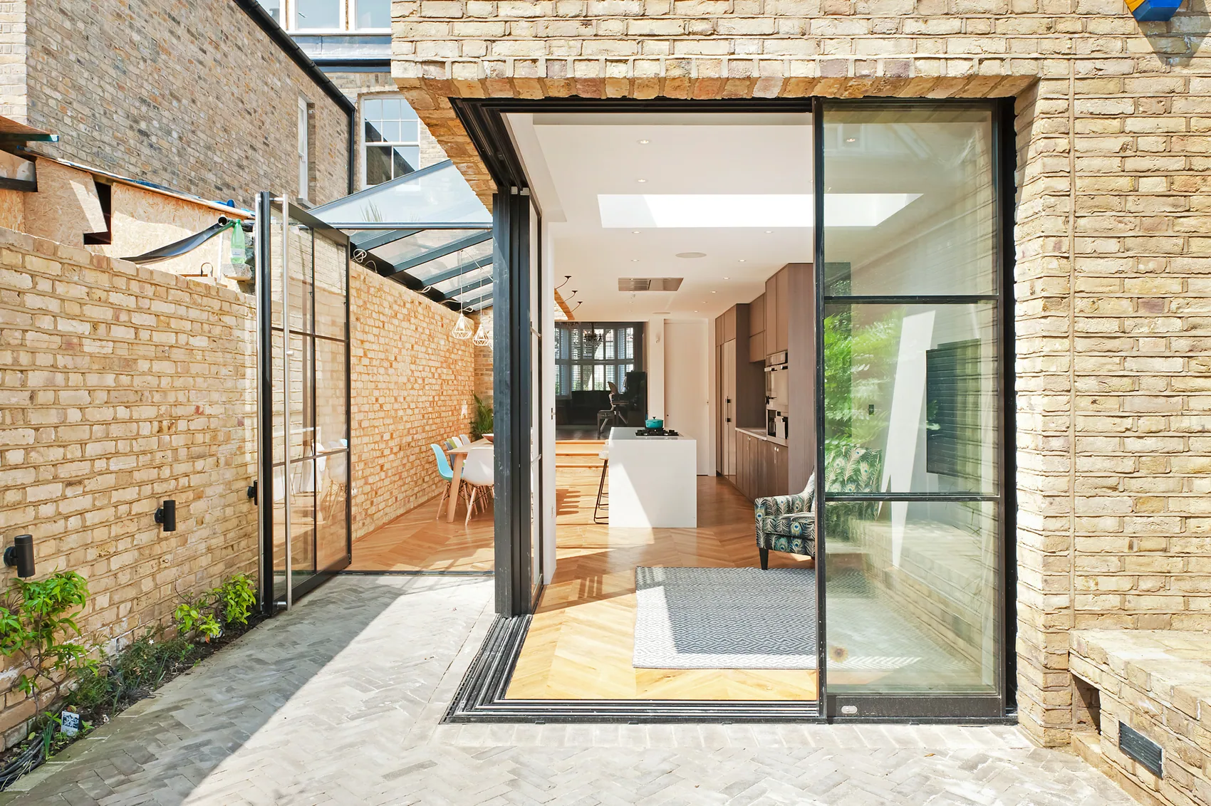 S-Max pivot door open across a sheltered courtyard threshold