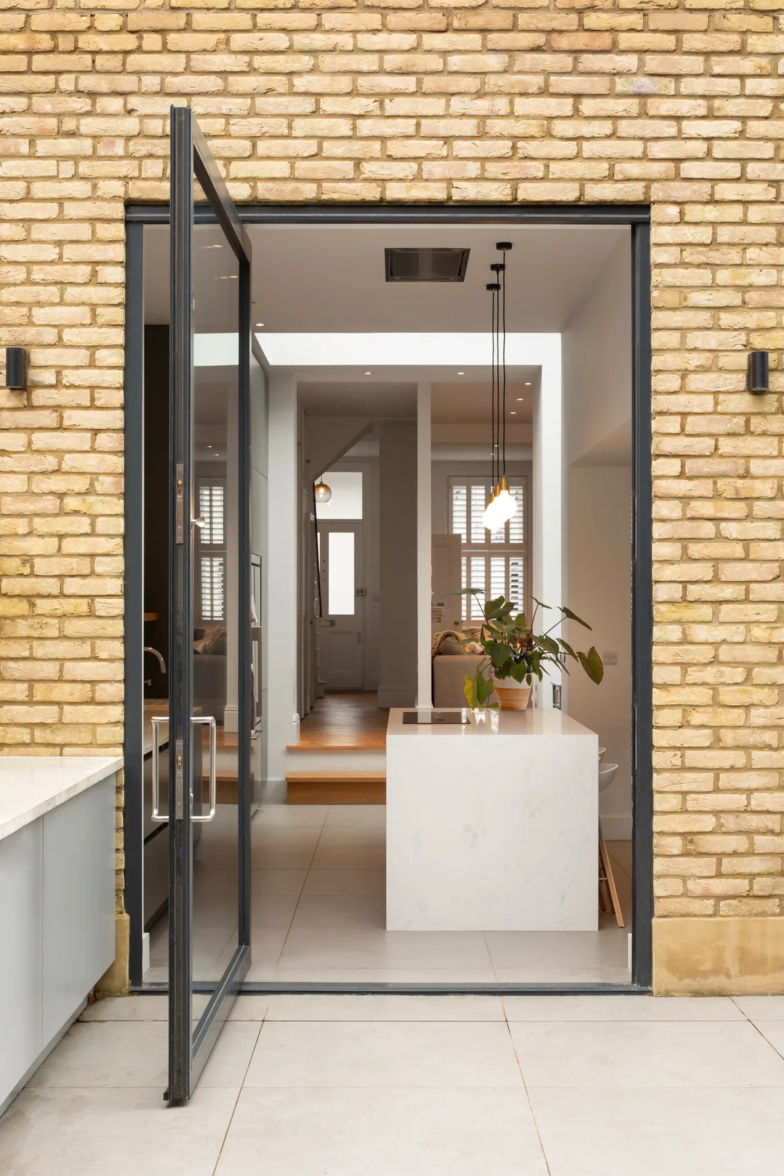 X-Max framed pivot door open inside a brick residential extension