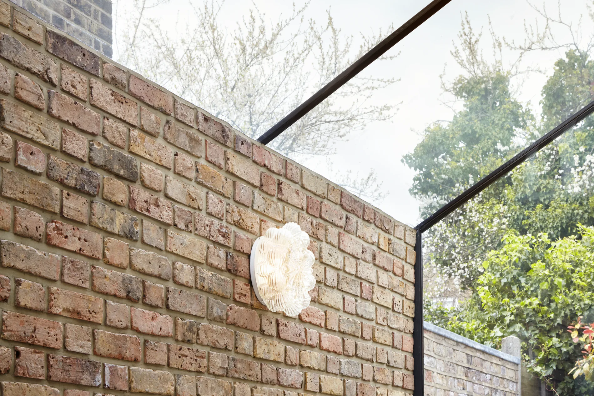 Brick interior wall with up-and-over glazing continuing from roof to facade
