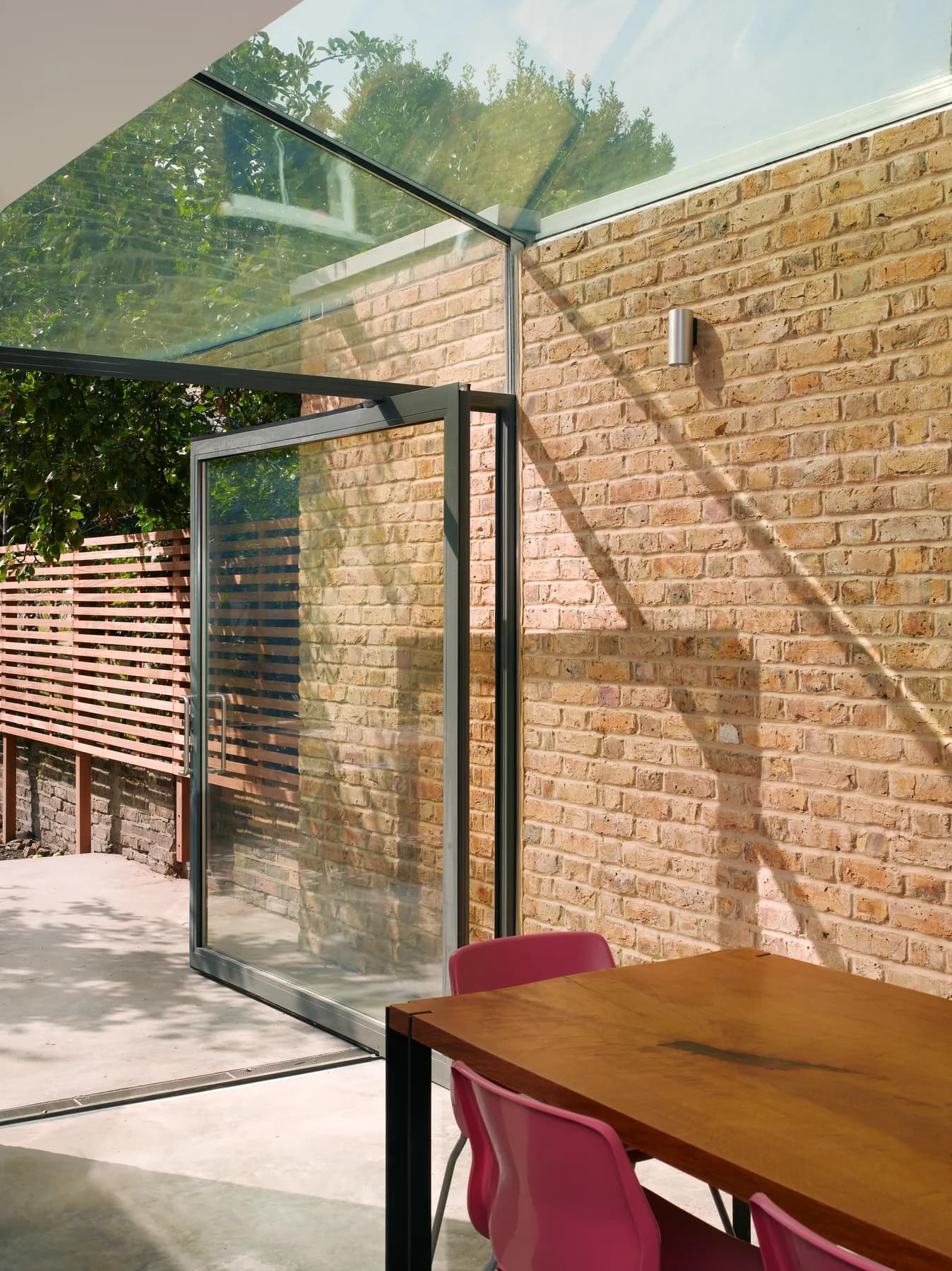 Glazed roof and vertical glass beside a brick wall and red chair