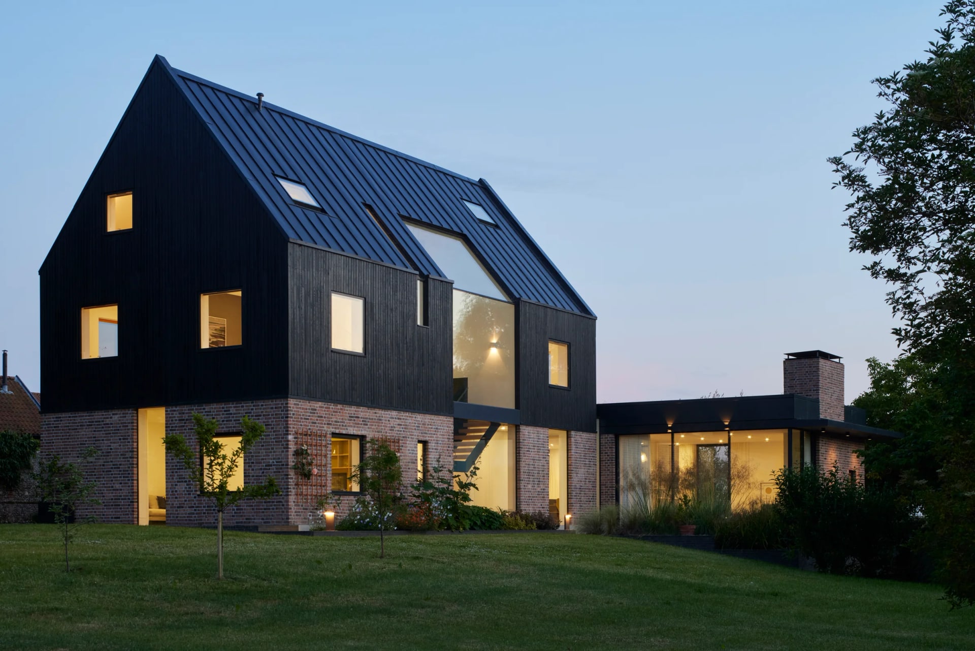 Contemporary brick house with aluminium rooflights and warm evening interior light