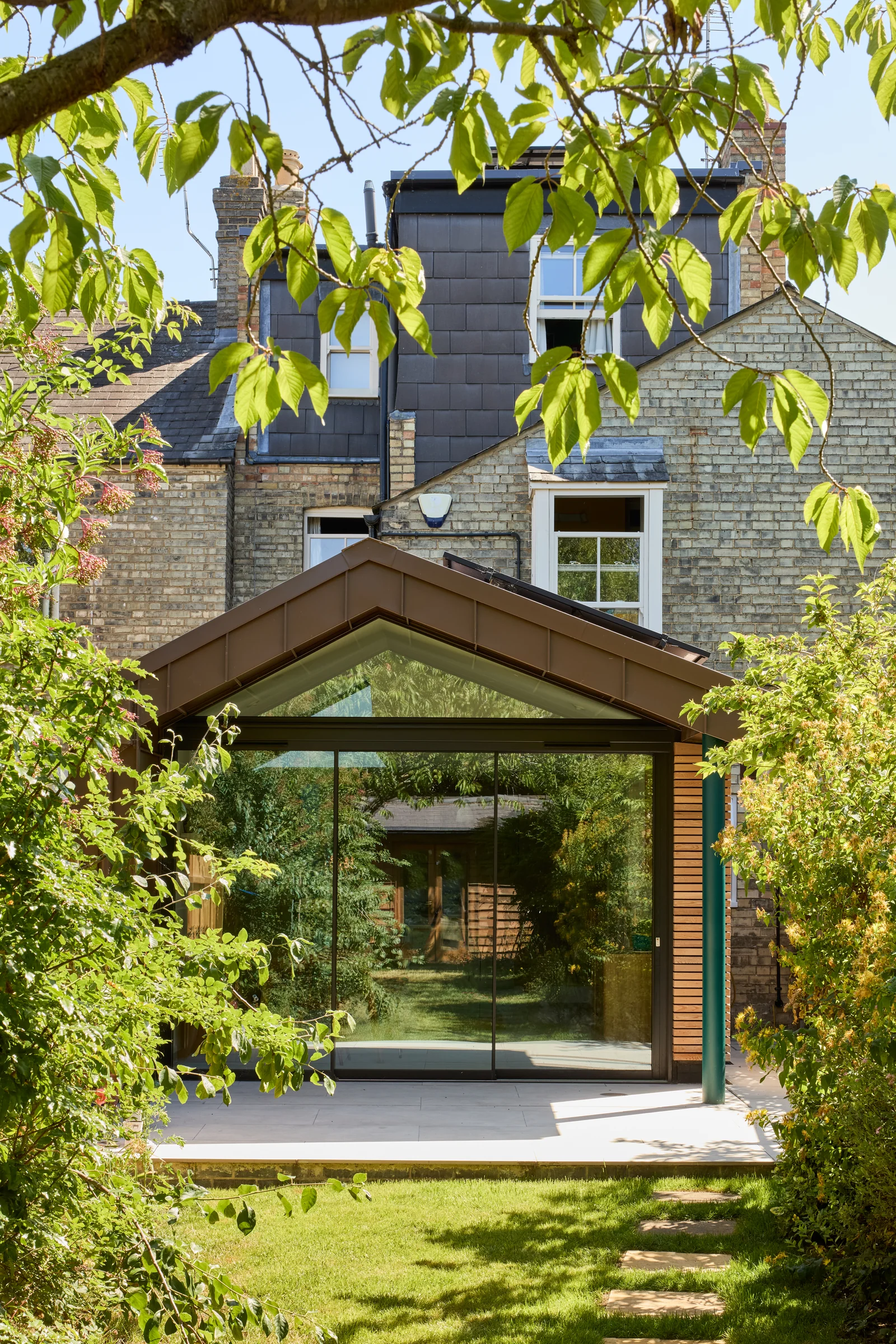 Ultra-slim aluminium sliding doors on a glazed garden extension framed by mature planting