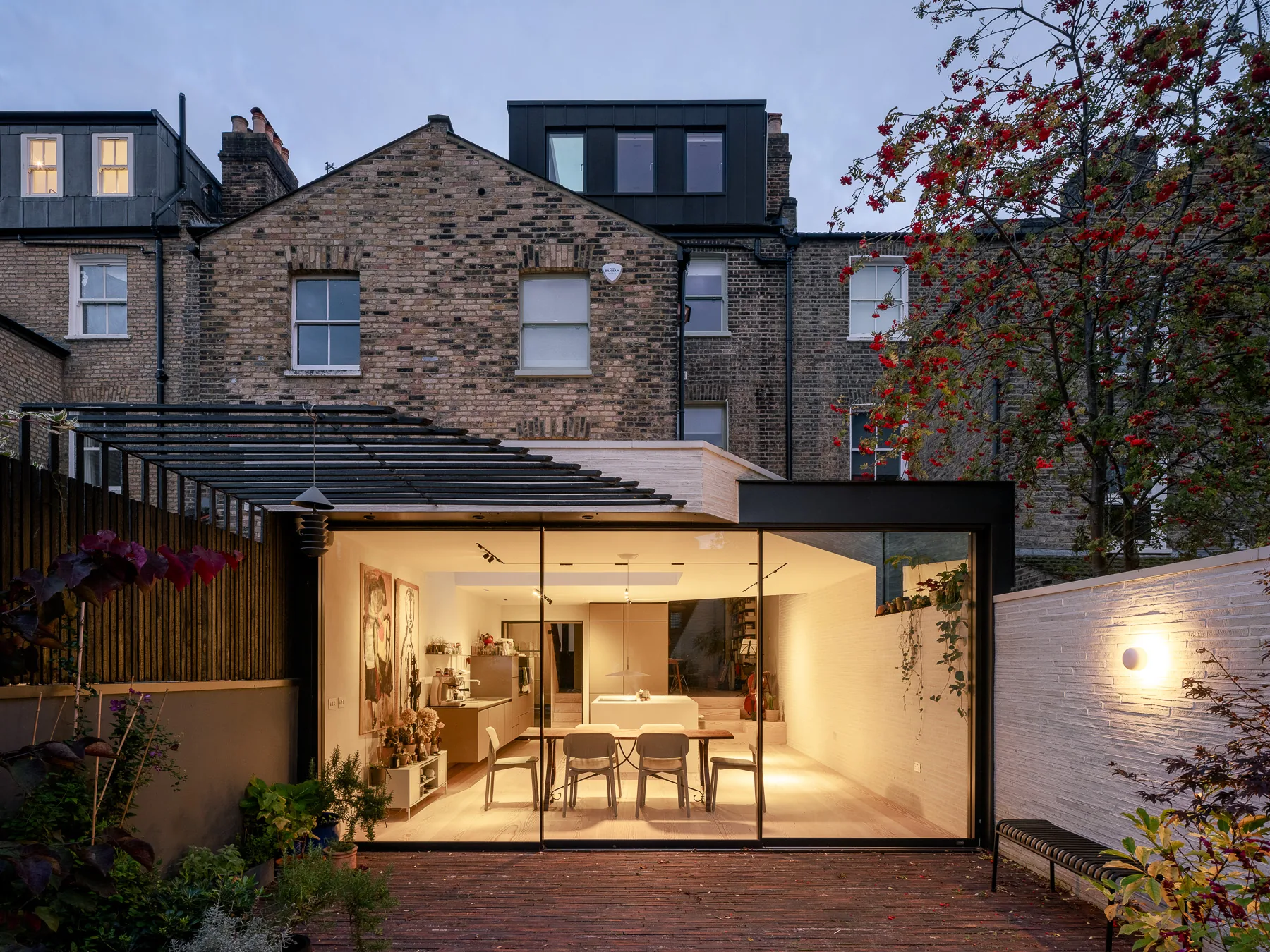 Wide triple sliding-door elevation illuminating a rear extension at dusk