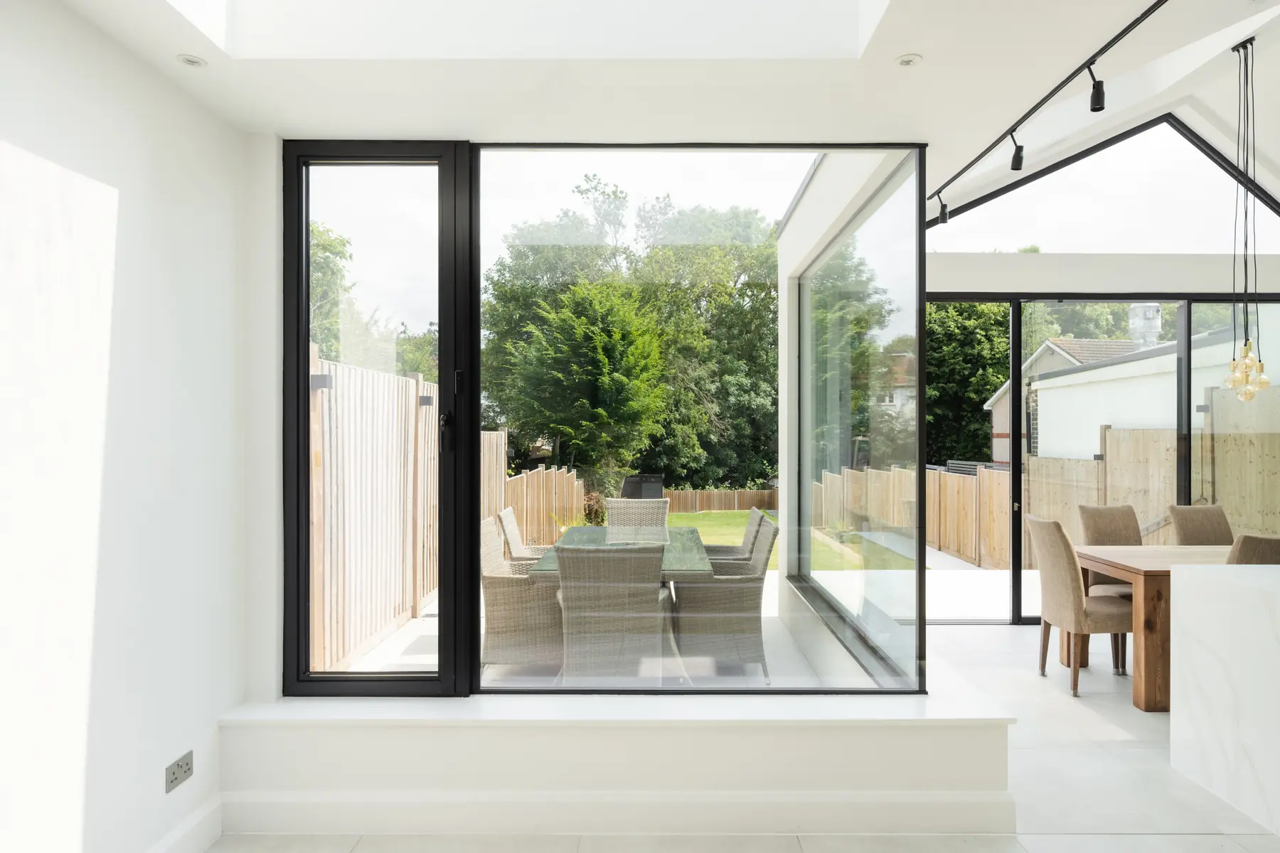 Living space with frameless glass corner and garden view