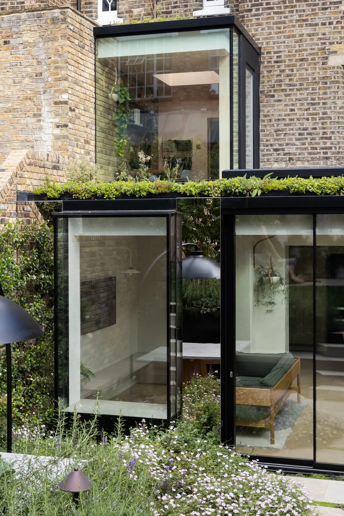 Exterior glass-to-glass corner with planted roof edge and brickwork
