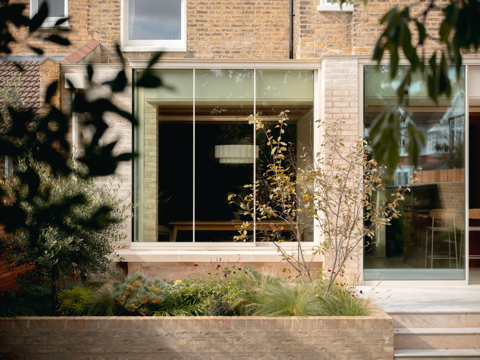 Slim-framed aluminium windows in a brick facade overlooking a planted garden