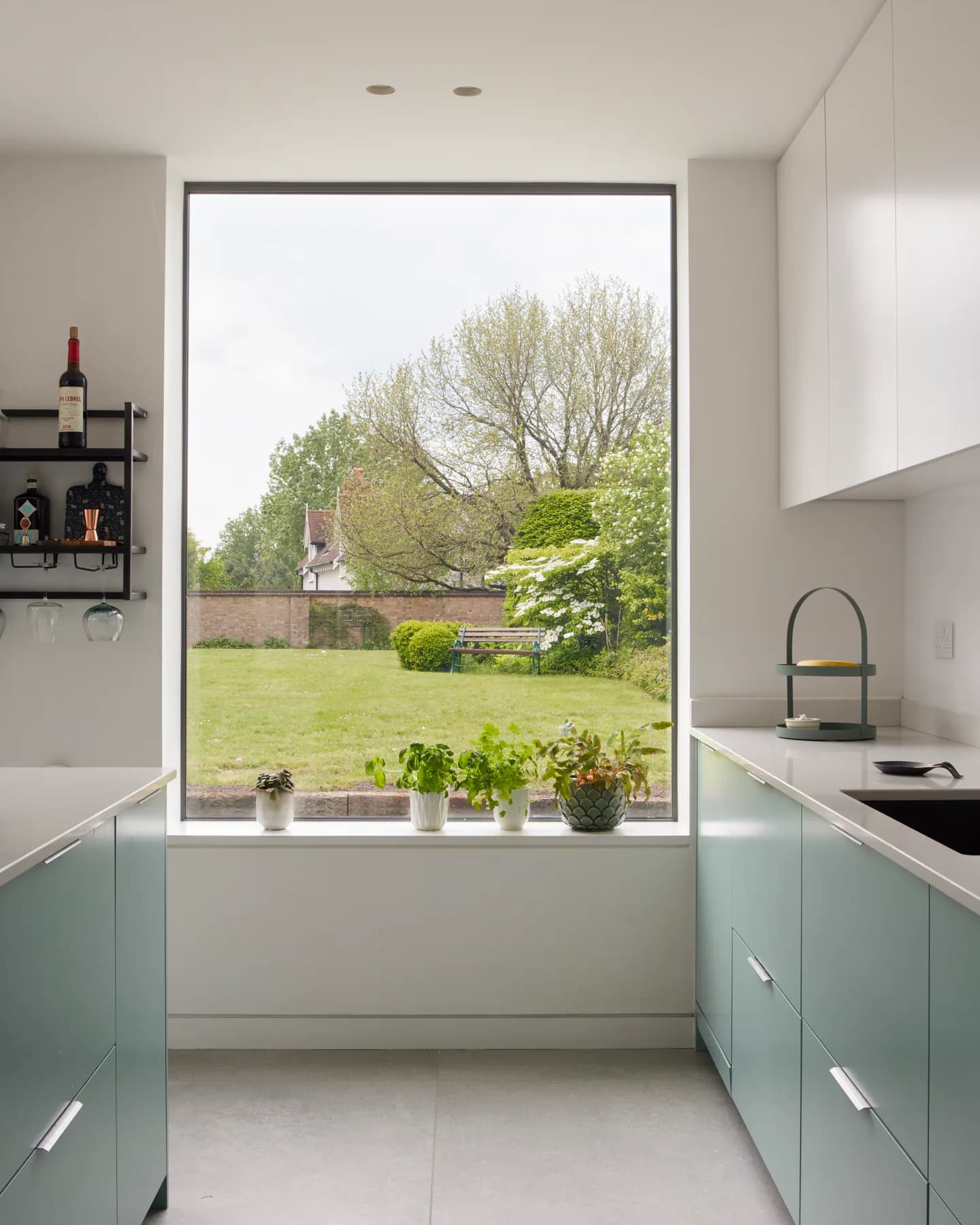 Fixed aluminium picture window above a kitchen sink framing a garden view