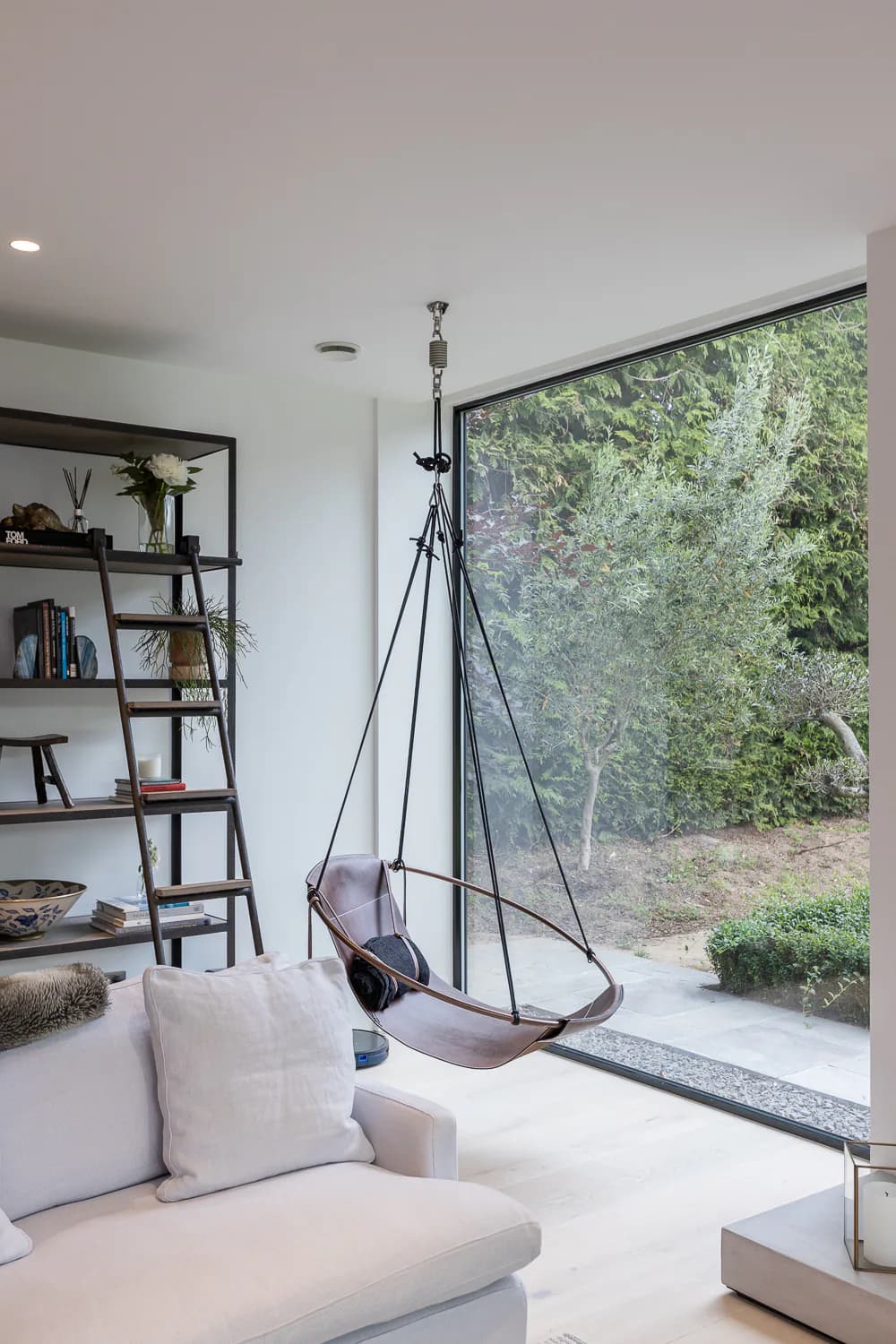 Corner fixed windows opening a contemporary living room towards mature trees