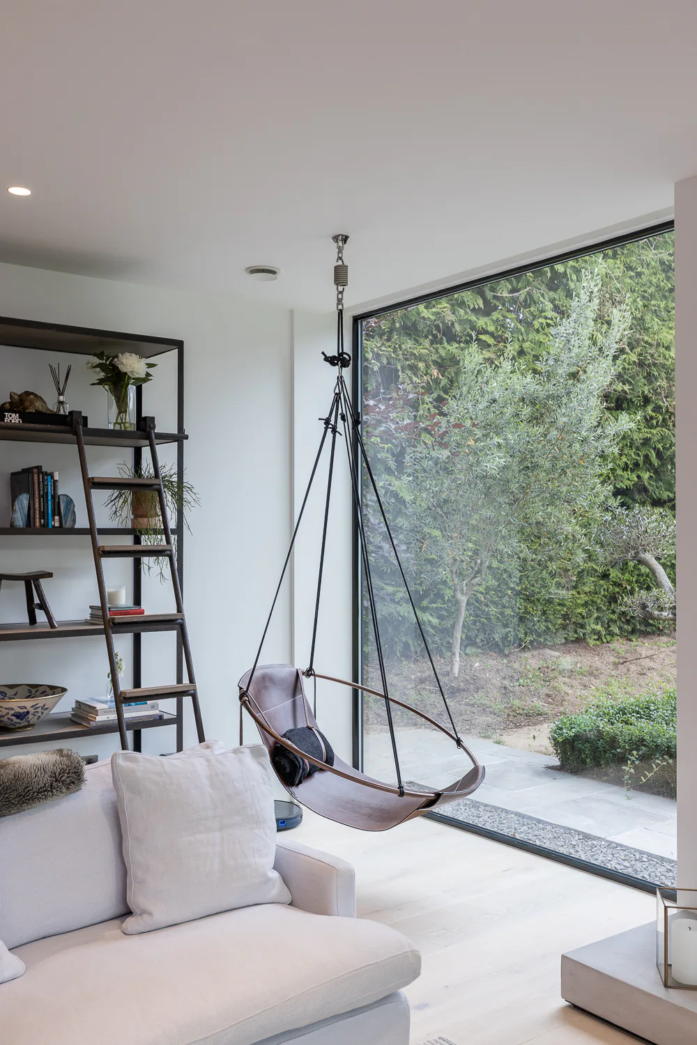 Corner fixed windows opening a contemporary living room towards mature trees