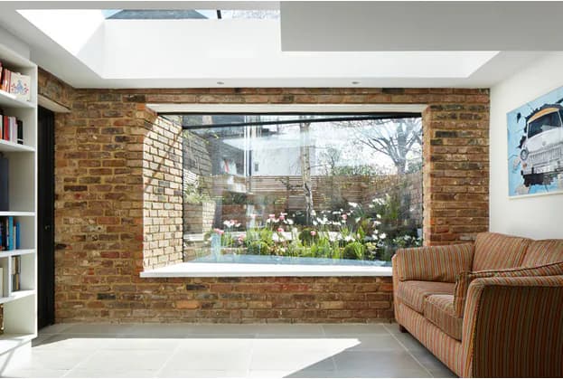 Deep-set oriel bay window framed by exposed brick inside a bright room