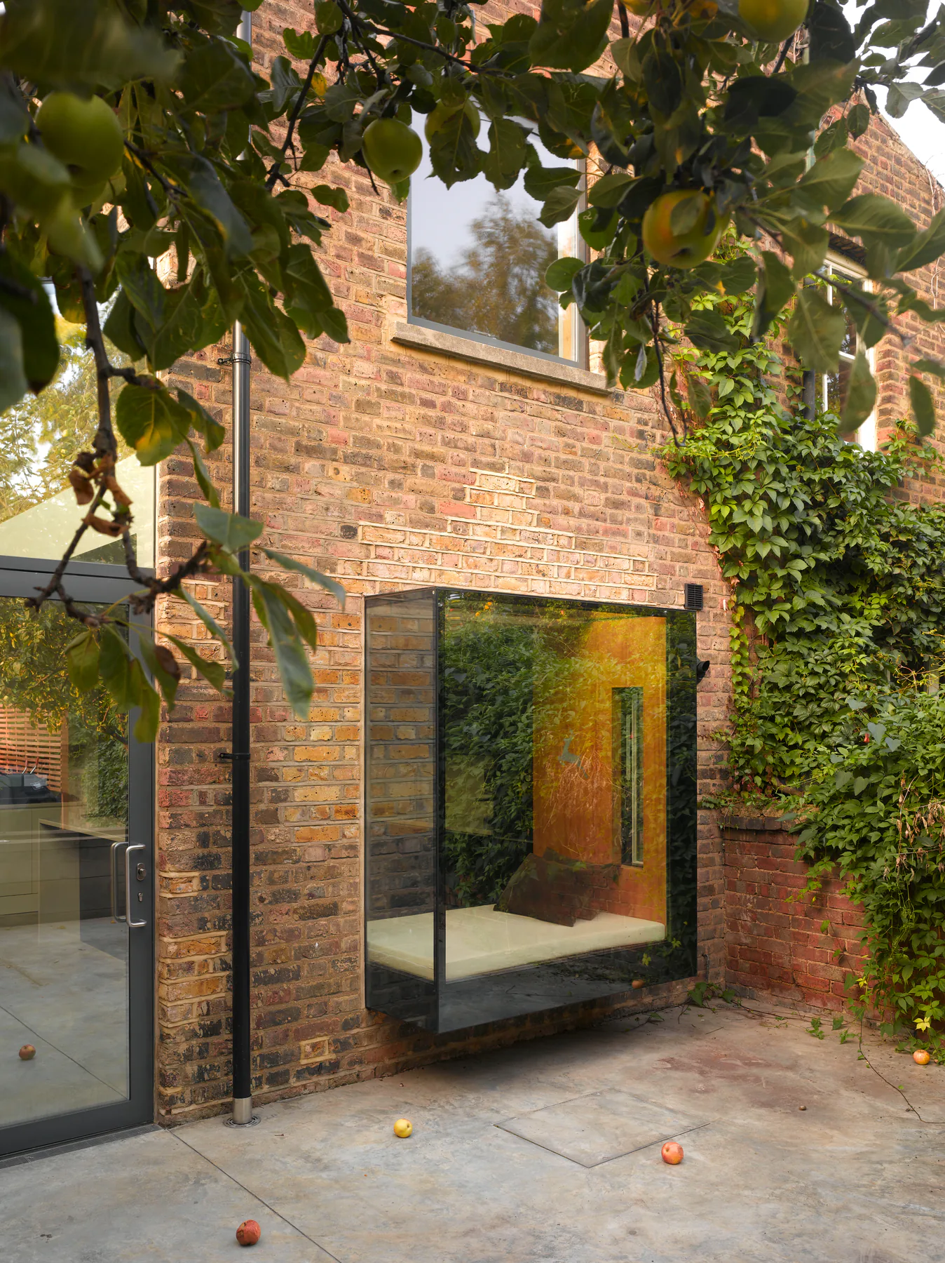 Black-framed oriel window projecting from a brick garden extension