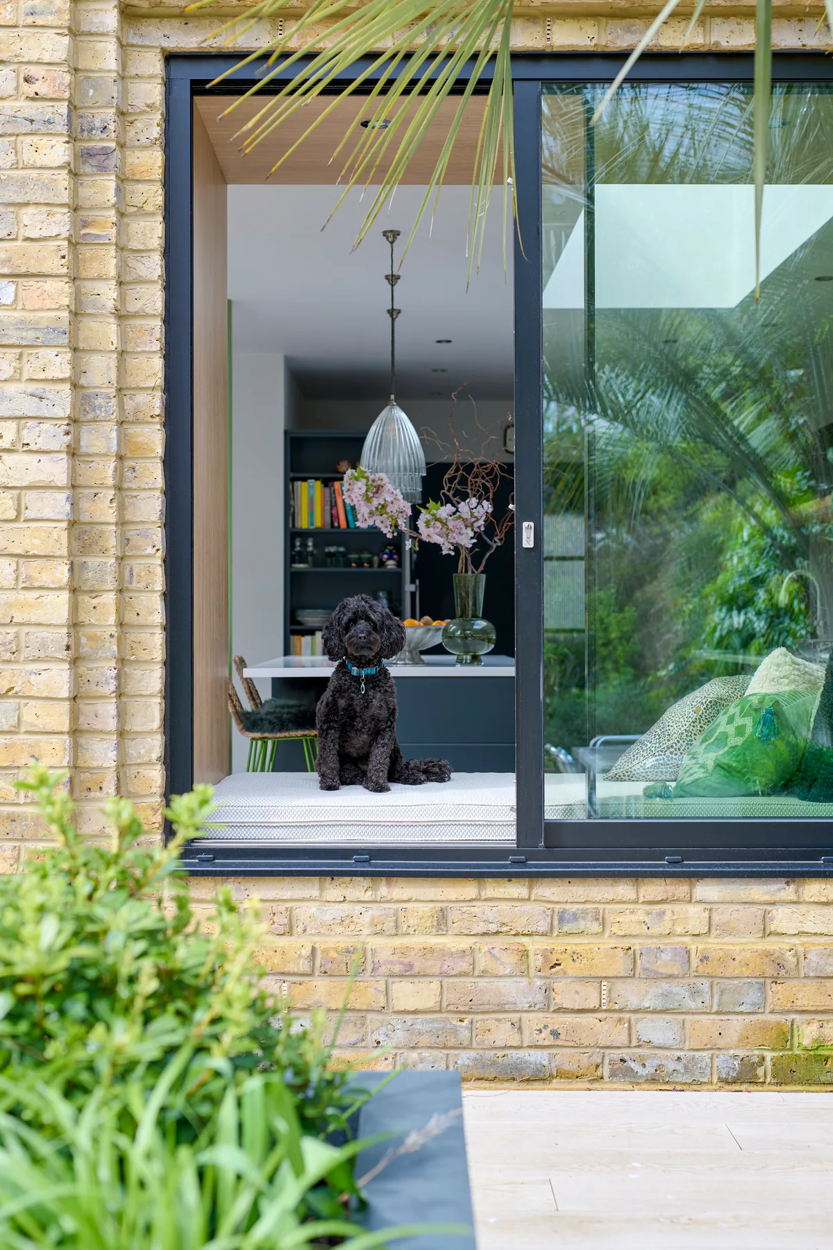 Tall sliding window opening onto the garden of a brick house
